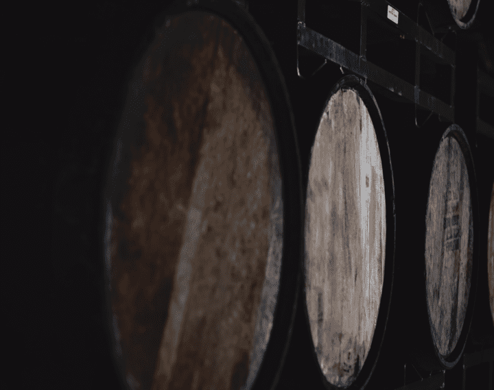Wooden barrels stacked in a low light setting of the winery