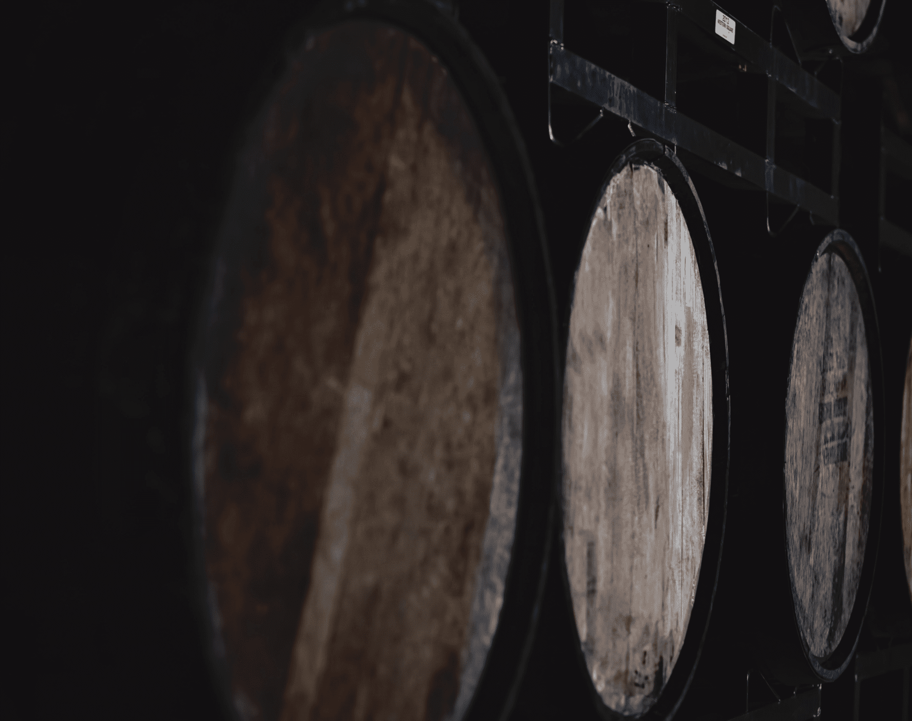 Wooden barrels stacked in a low light setting of the winery