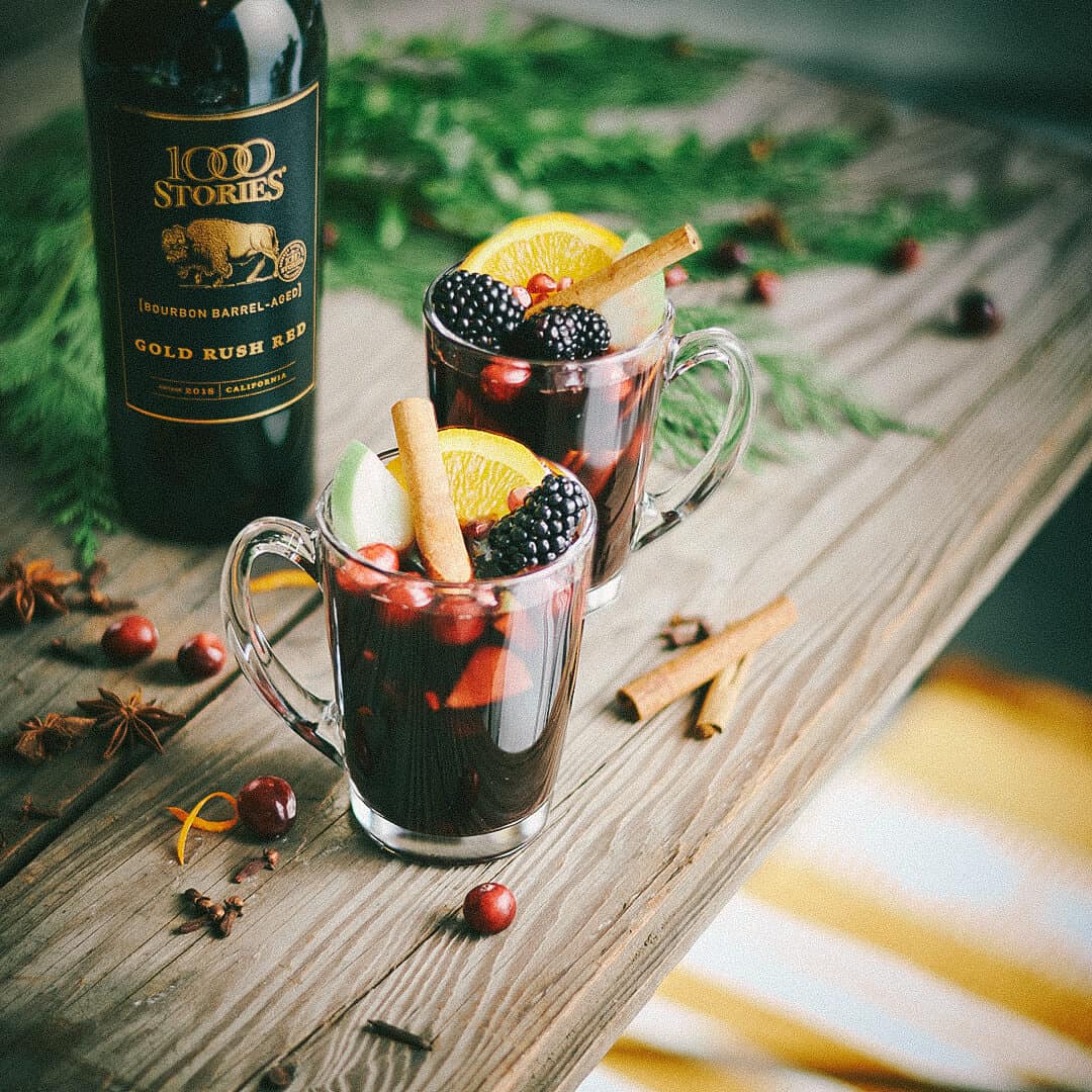 Mulled Wine Sangria with fruit and a bottle of wine on a table that's decorated for the holidays